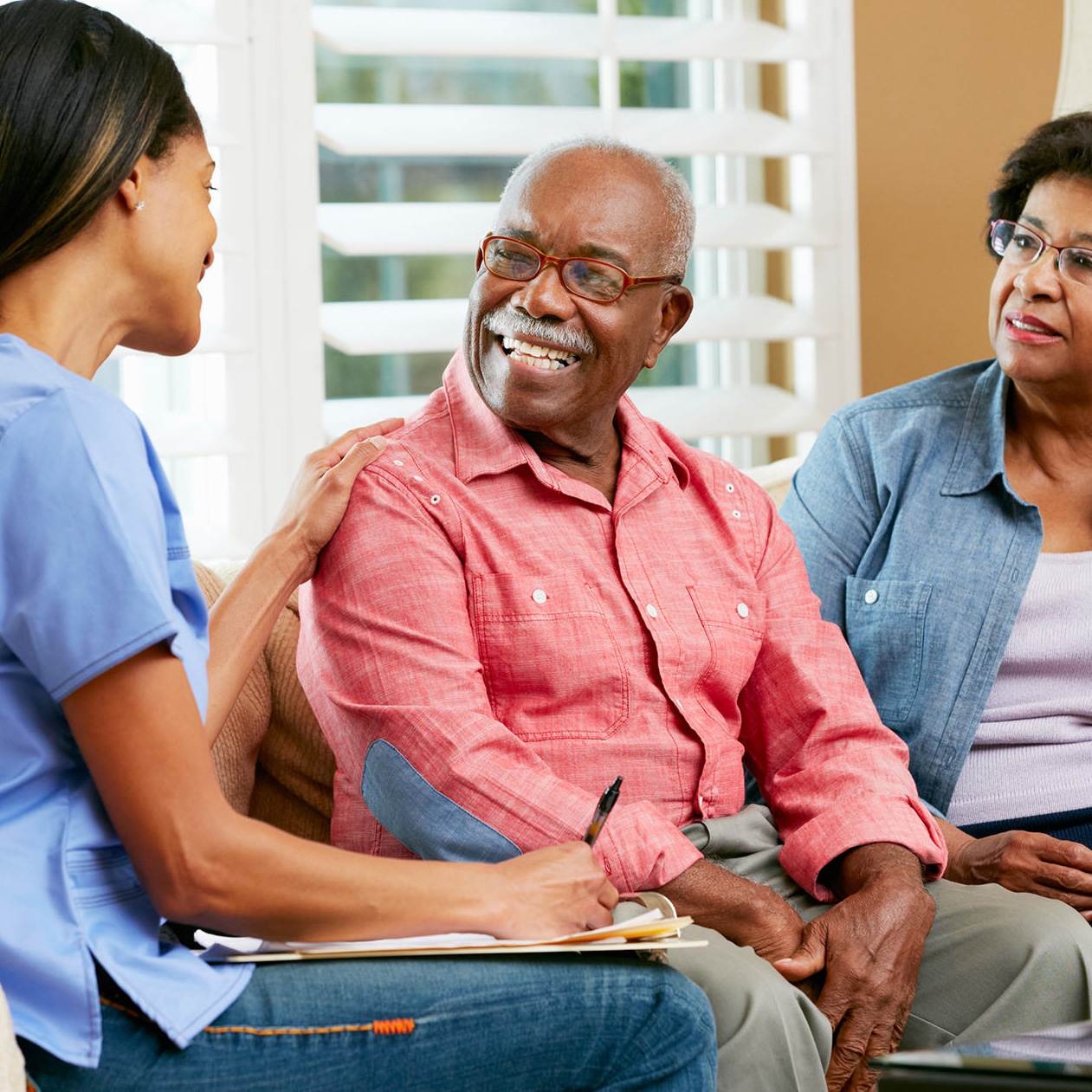 Nurse Making Notes During Home Visit With Senior Couple