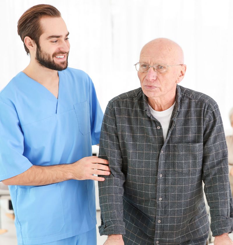 Male Caregiver Assisting Senior Man With Walking Frame